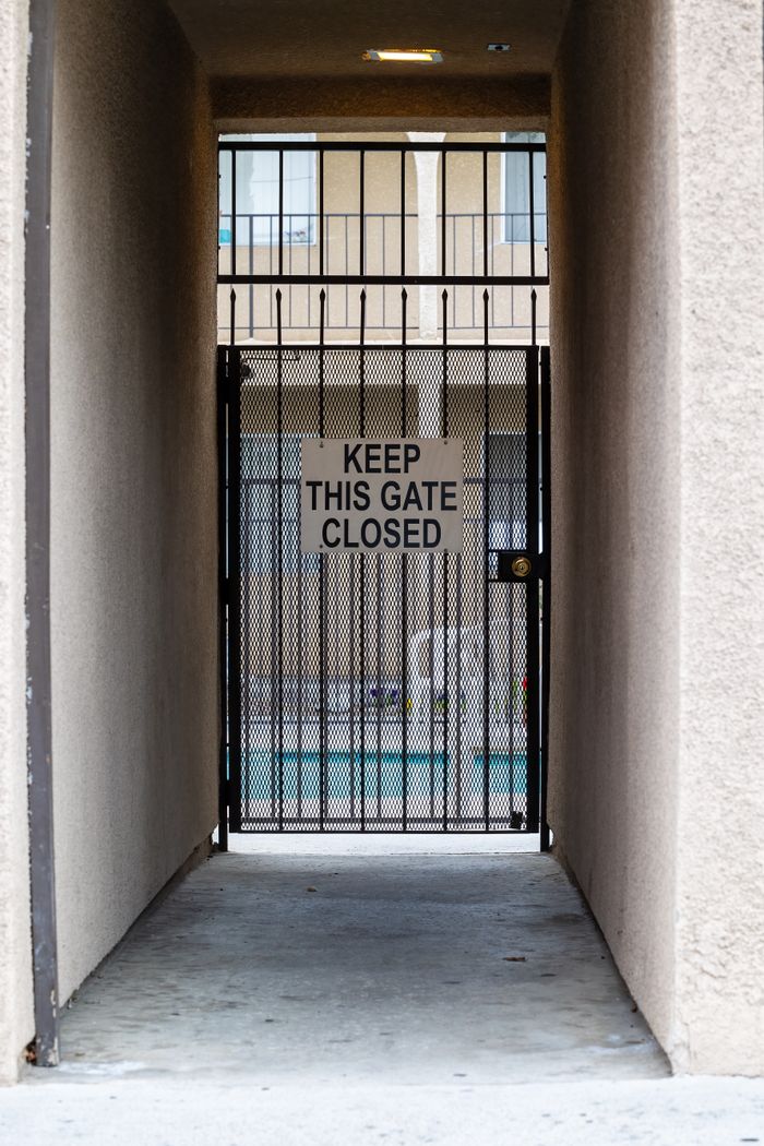 services-04 View of a narrow passage leading to a gated pool area with a warning sign.