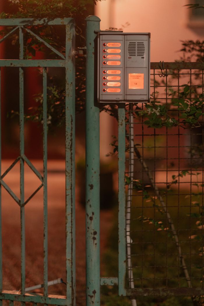 services-03 Rustic intercom system mounted on a weathered garden gate during nighttime in Italy.